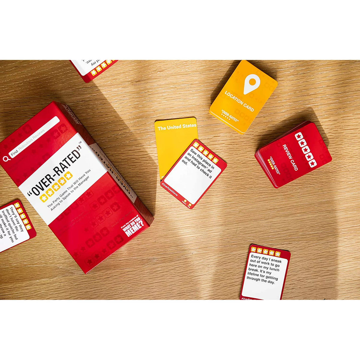 Top-down view of the red box, location card and review card decks on a wood table