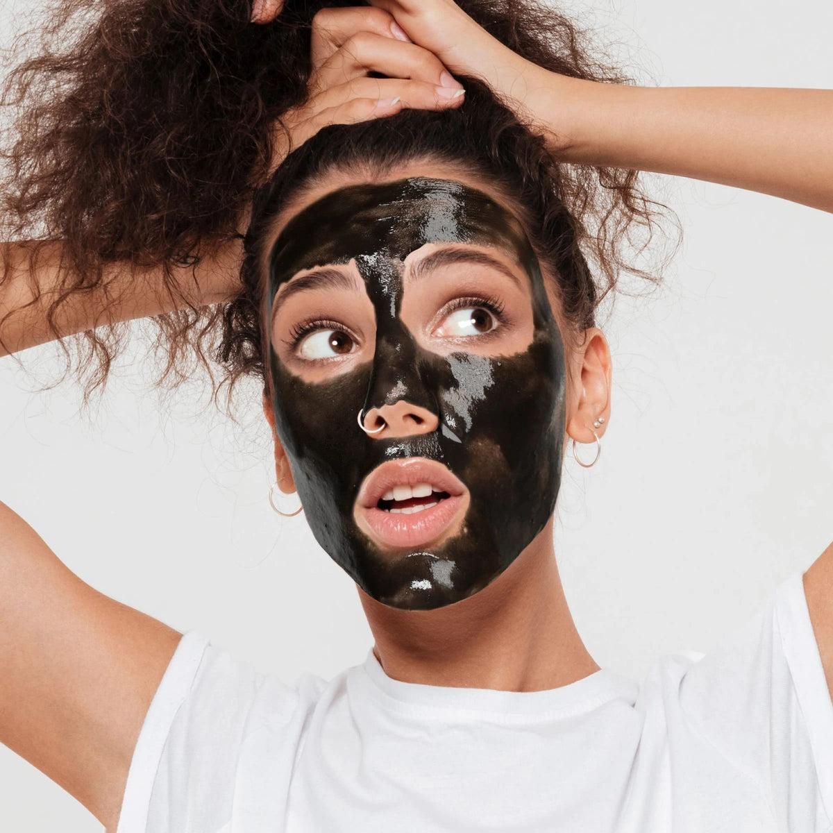 Woman with curly hair wearing a glossy black peel-off mask over her face