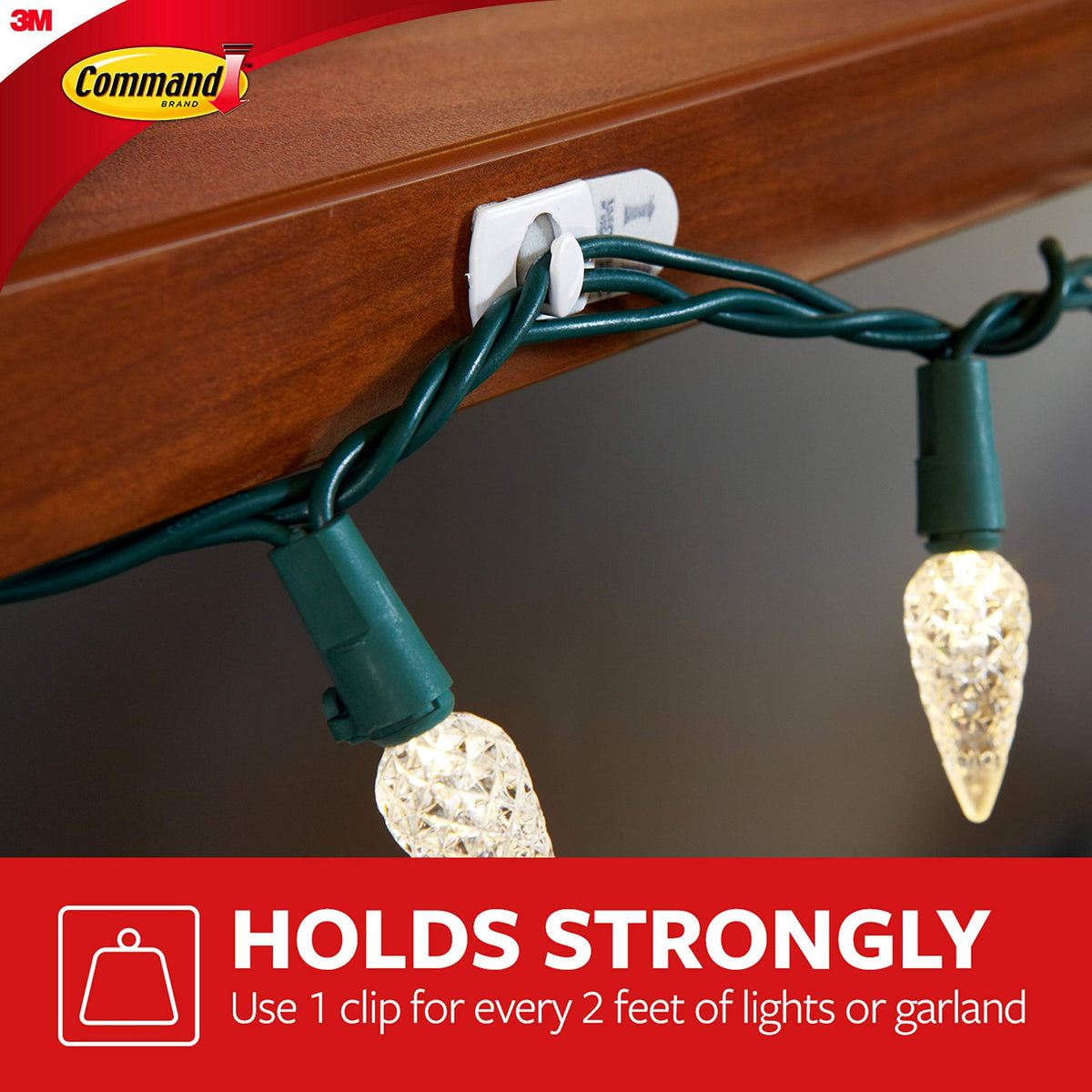 White clip holding a green string of warm white lights under a wooden shelf edge