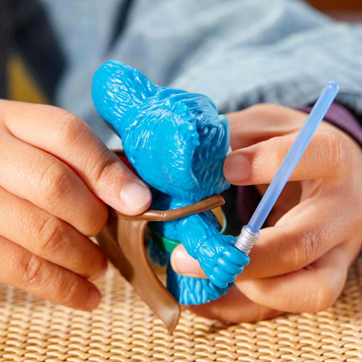 Hands clipping the brown cape onto the back of the blue figure