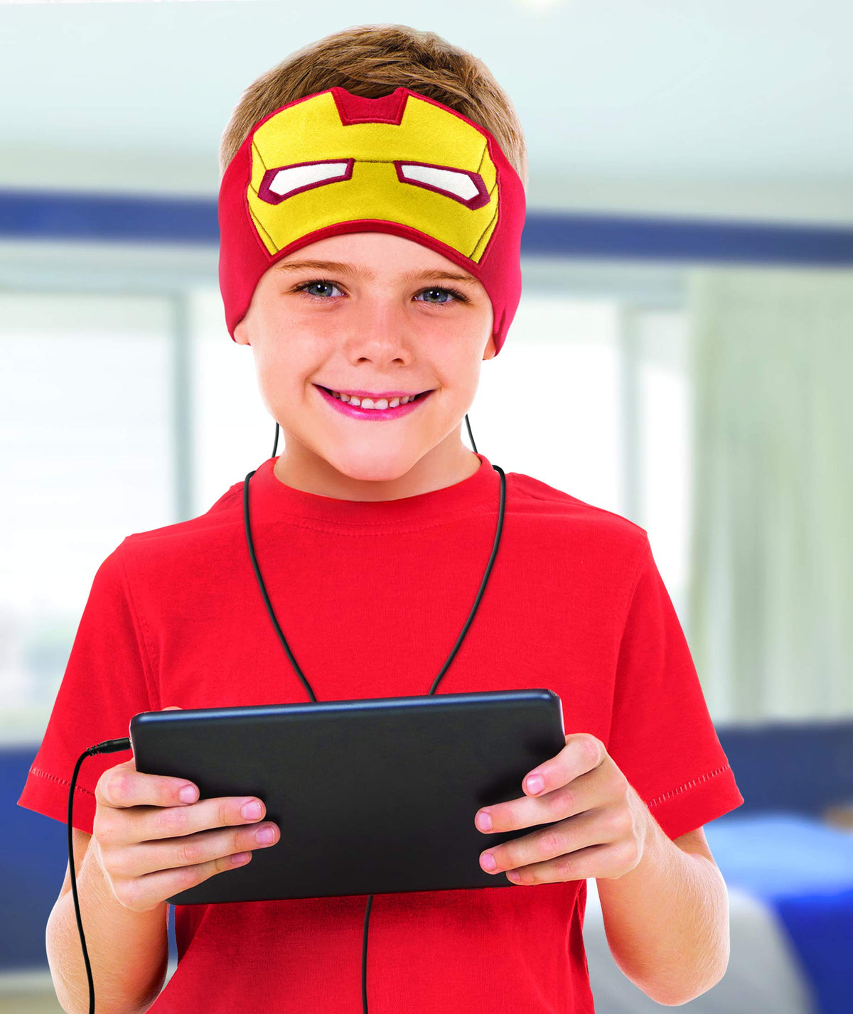 Smiling boy in a red T-shirt wearing the mask headband headphones, plugged into a tablet