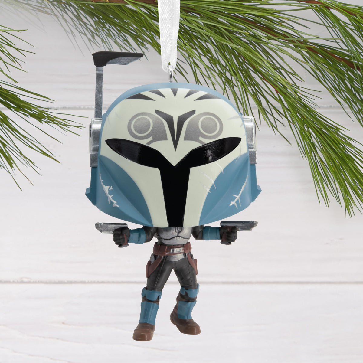 Blue-helmeted vinyl warrior ornament hanging from a pine branch