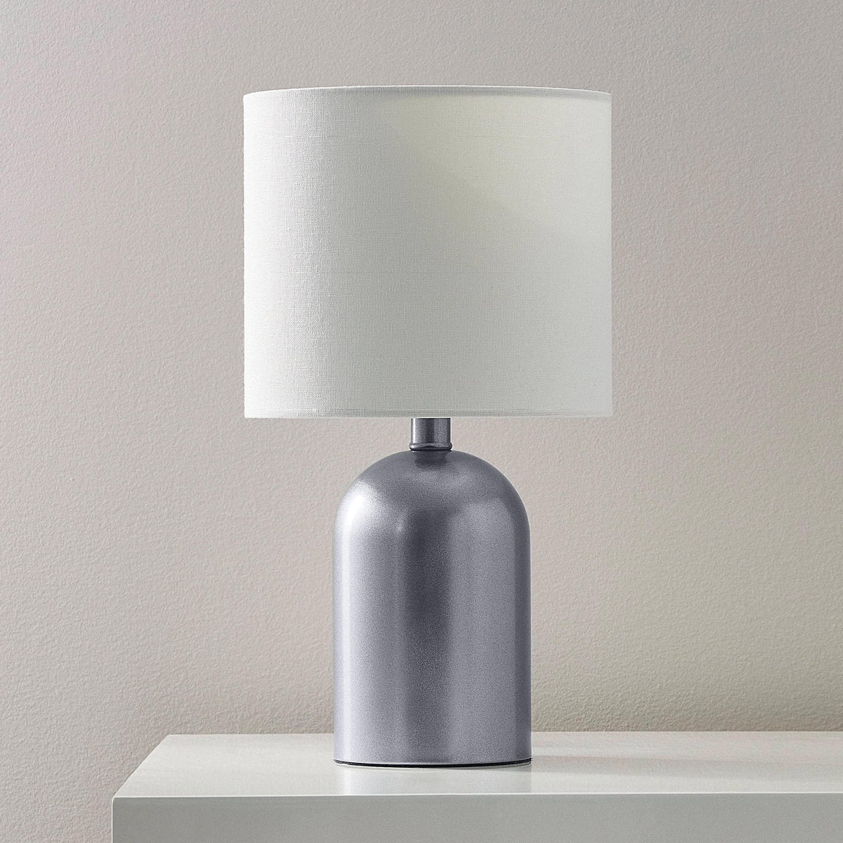 Table lamp with a dark steel metallic base and white drum shade