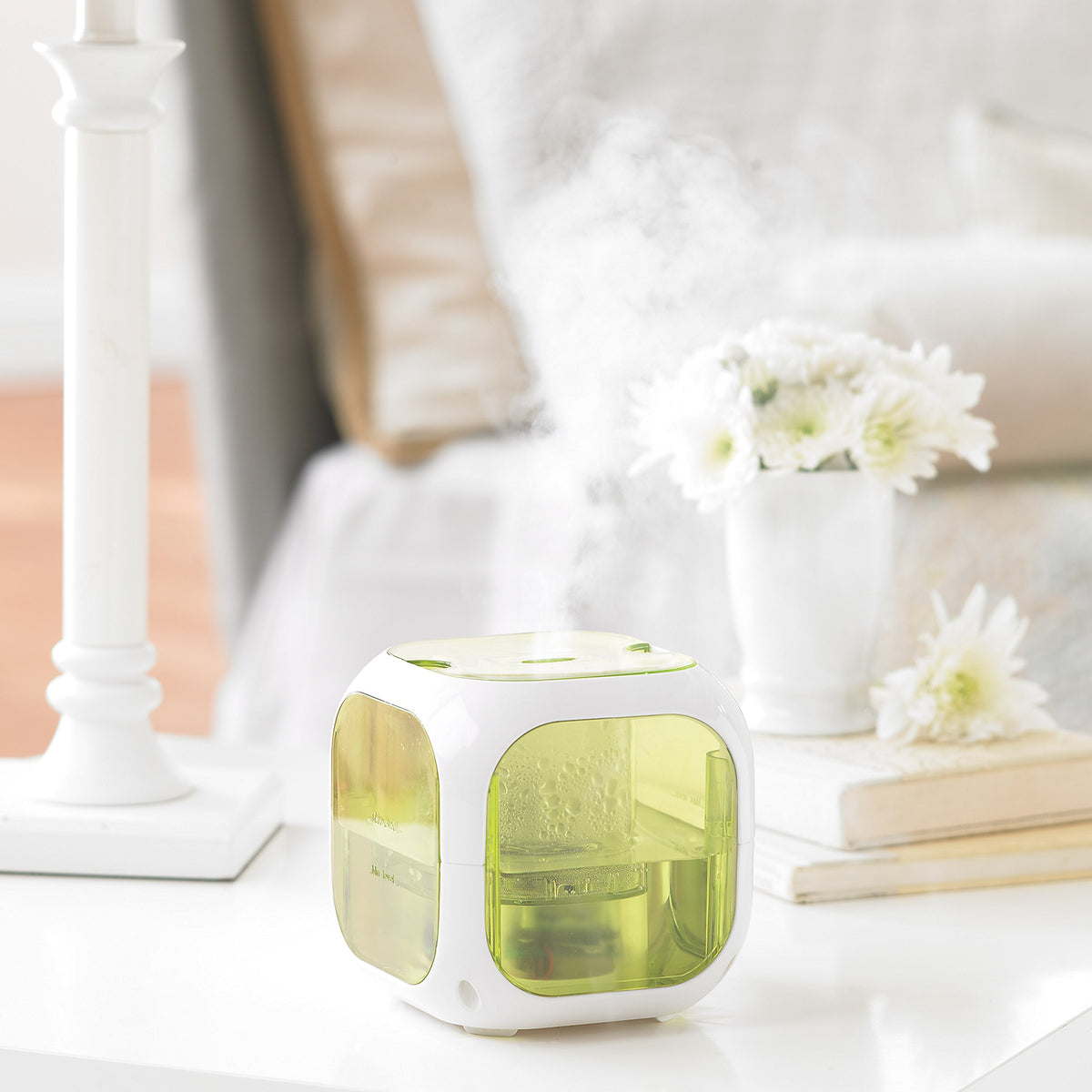 Cube humidifier misting on a white nightstand beside a vase of white flowers