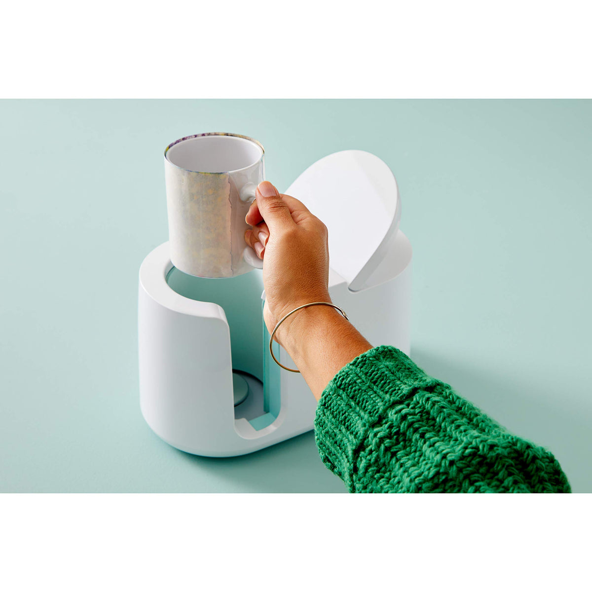 Hand placing a mug wrapped in an Infusible Ink transfer into the open Mug Press