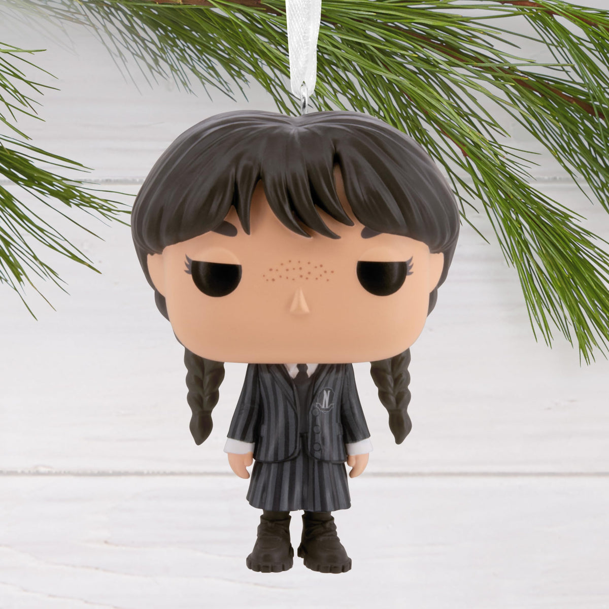 Braided girl vinyl ornament hanging from a pine branch