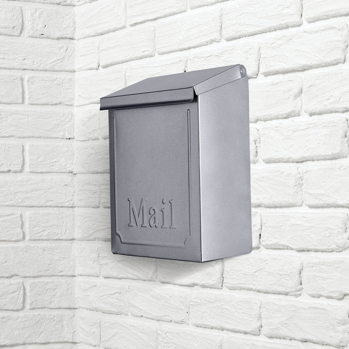 Wall mailbox painted metallic grey on a white brick wall