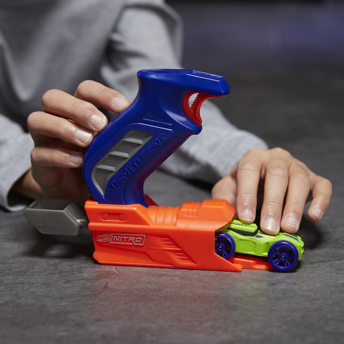 Close-up of hands loading the green car into the launcher