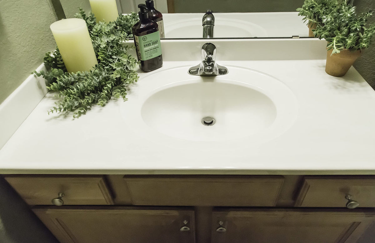 White vanity top with oval sink, chrome faucet, side splash and hand soap bottle