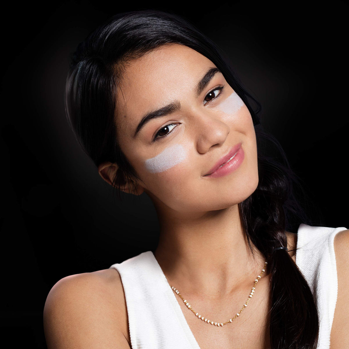 Smiling woman with stripes of pale clay mask on both cheeks