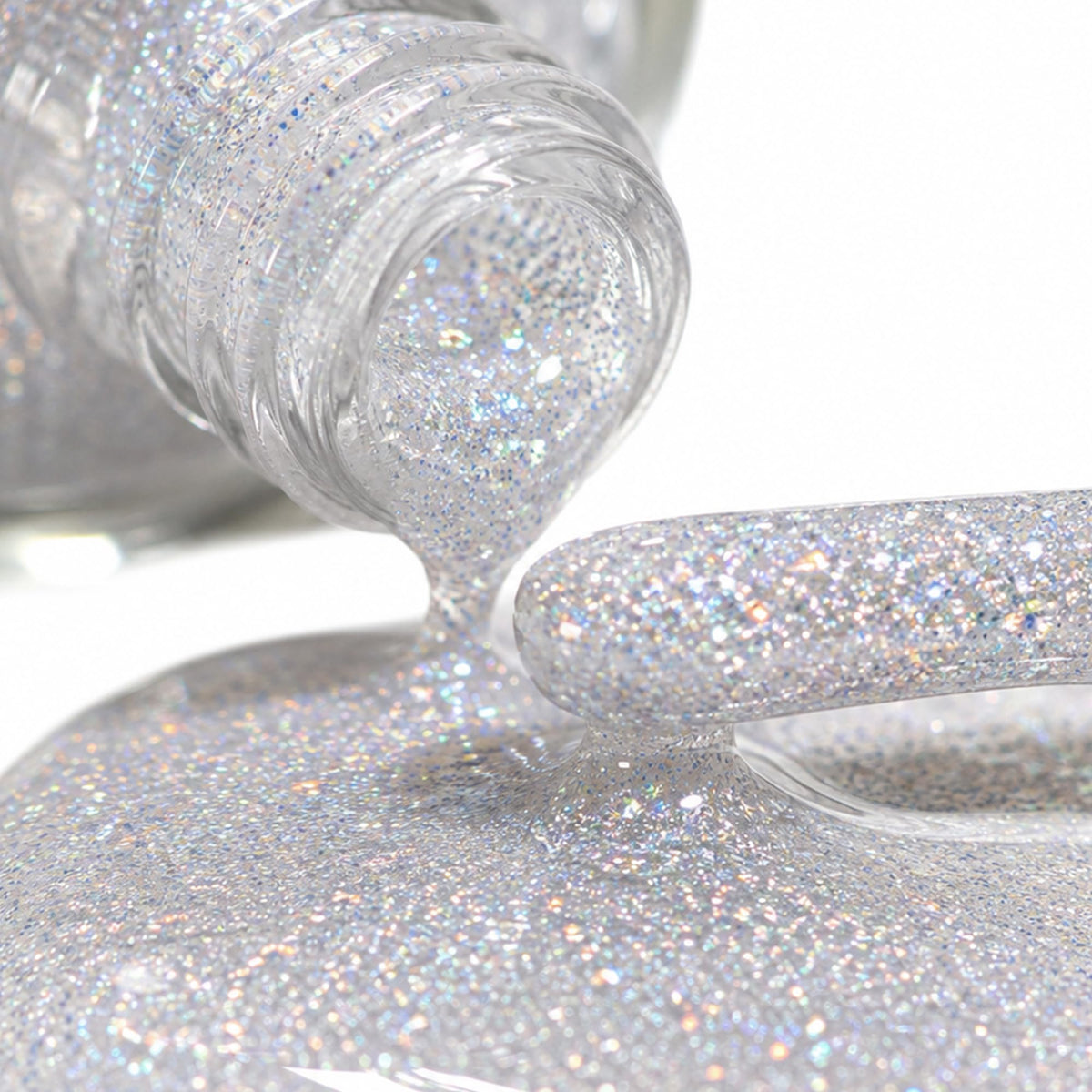 Silver holographic glitter polish pouring from a tipped glass bottle