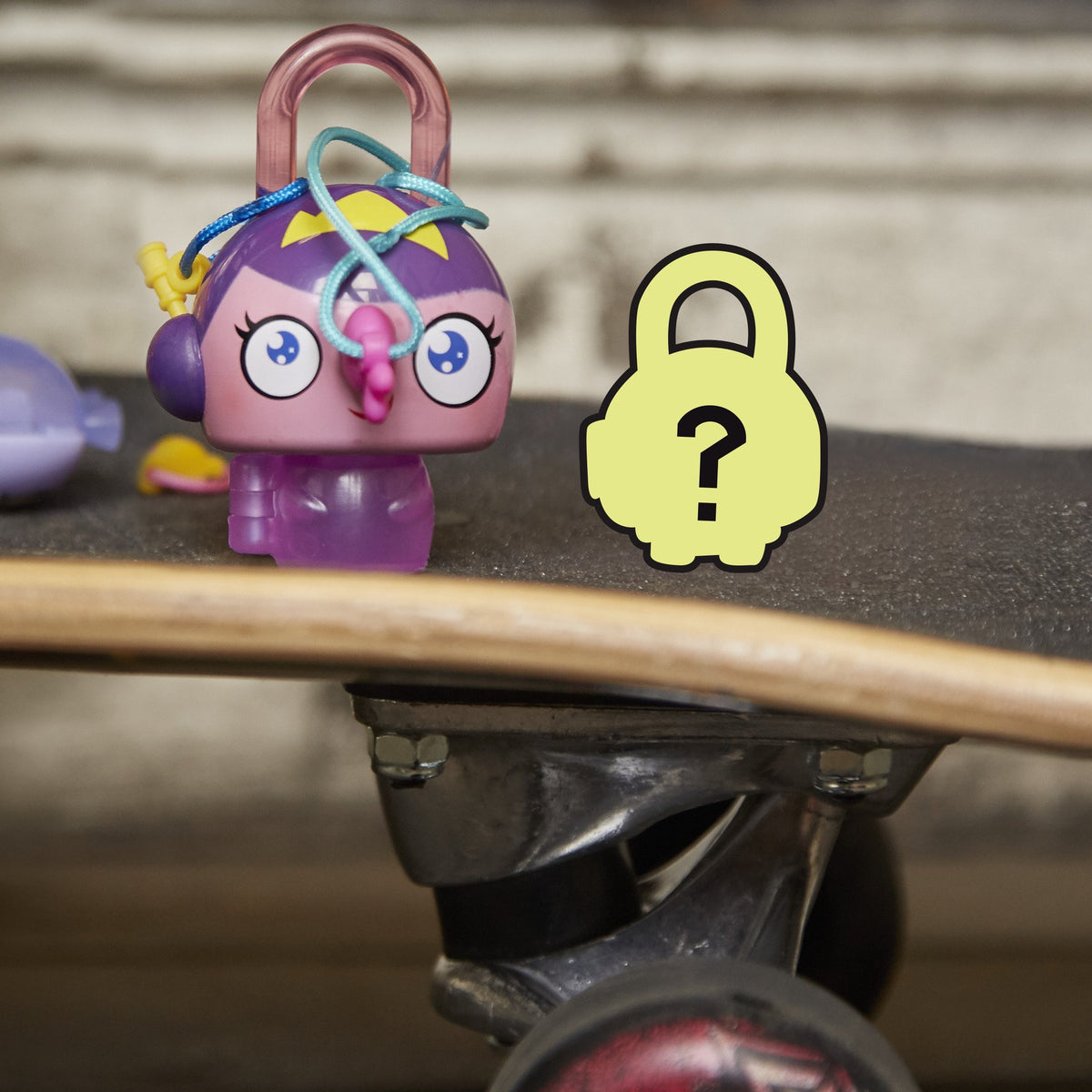 Purple princess padlock toy sitting on a skateboard deck next to a mystery lock card