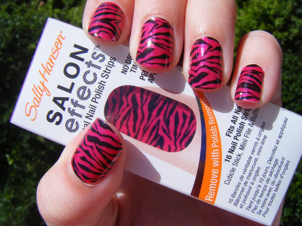 Hand with nails covered in pink zebra print strips holding the box outdoors