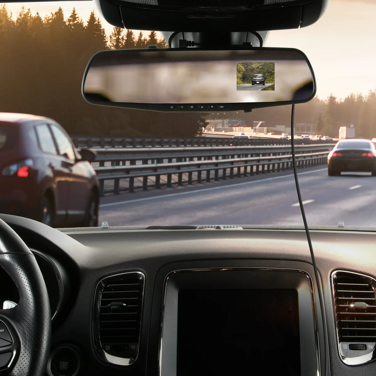 Mirror dash cam strapped over a car's rearview mirror with its screen showing the road