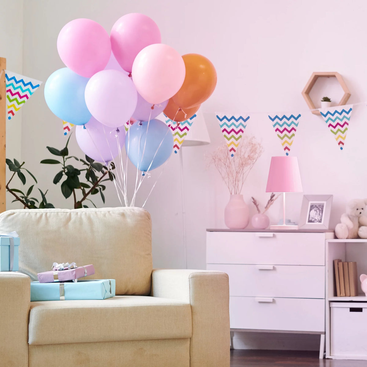 Party room with pastel balloons and bunting lit by a pink table lamp