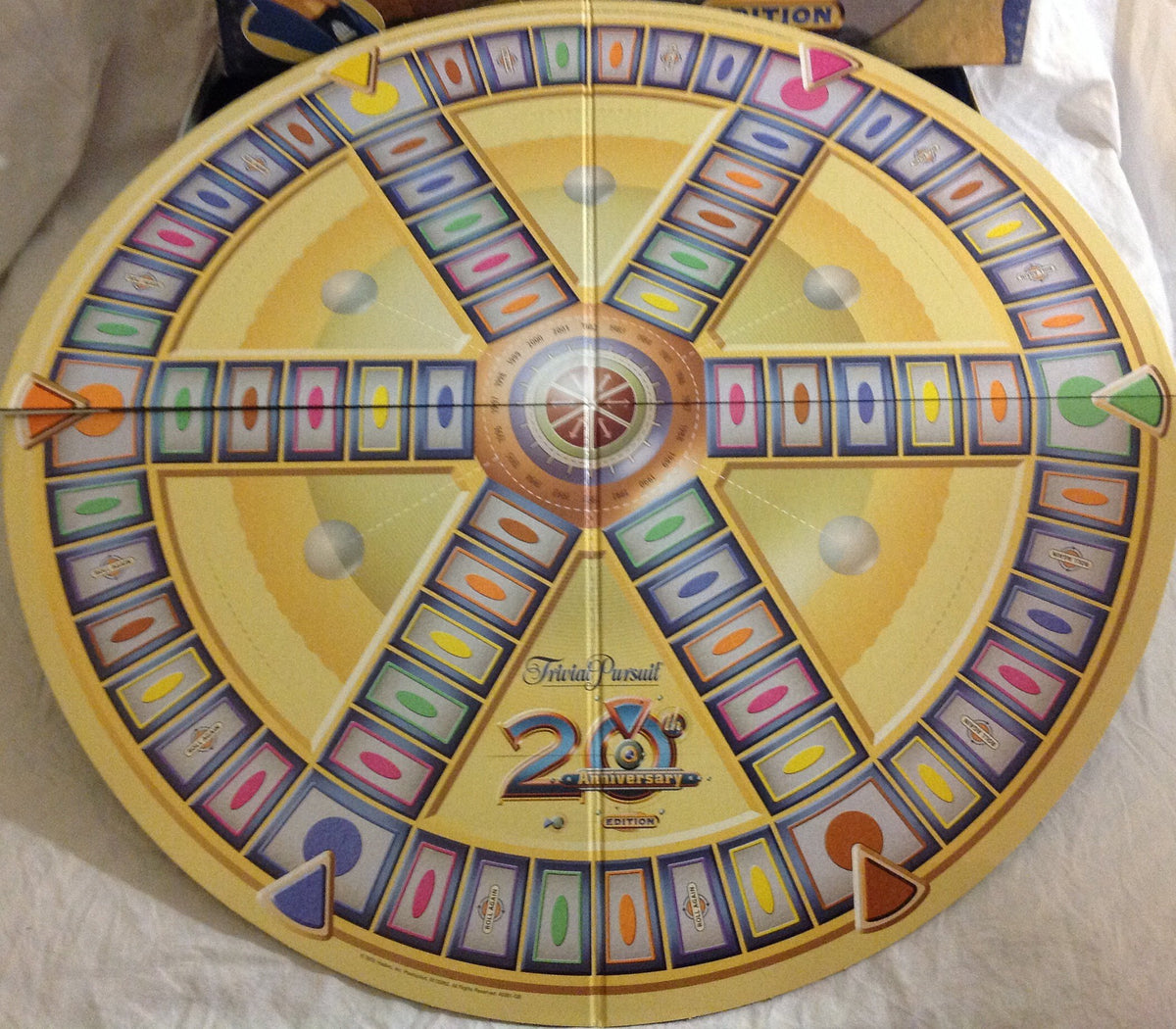 Round yellow game board with six spokes and coloured category spaces laid out flat
