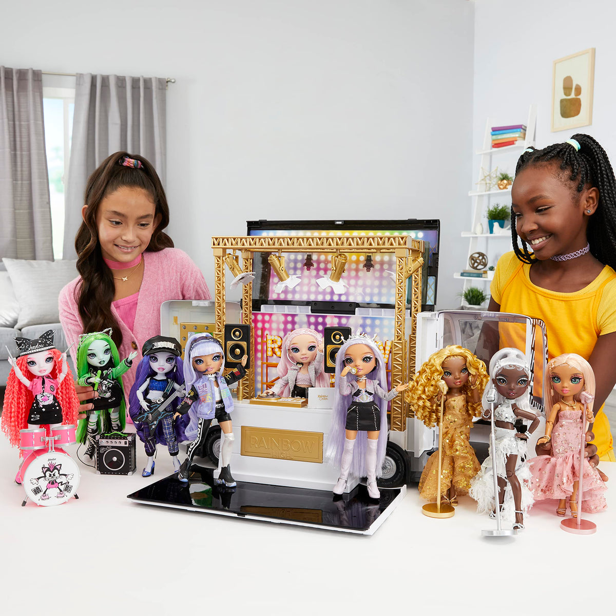 Two girls playing with a row of fashion dolls in front of a stage playset