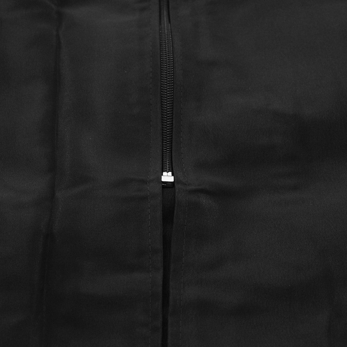 Close-up of the black front zip ending in a silver stop near the hem