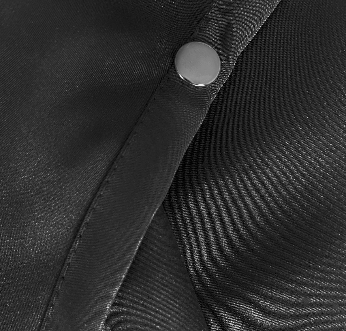 Close-up of a silver snap on the stitched black neck strap