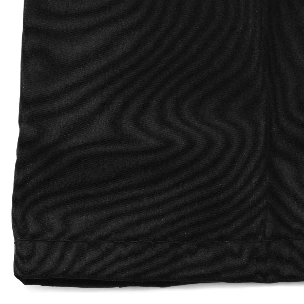 Close-up of the stitched hem at a corner of the black barber jacket