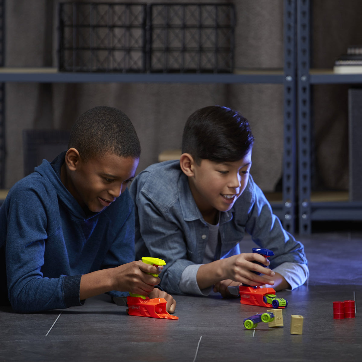 Two boys with yellow and blue launchers as foam cars knock over crates