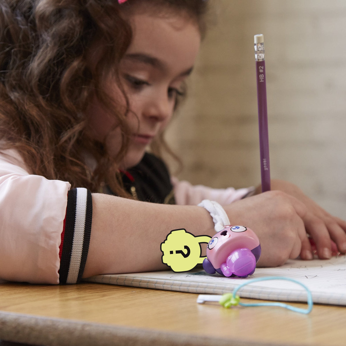Girl writing at a desk with the pink padlock figure clipped to her wrist band