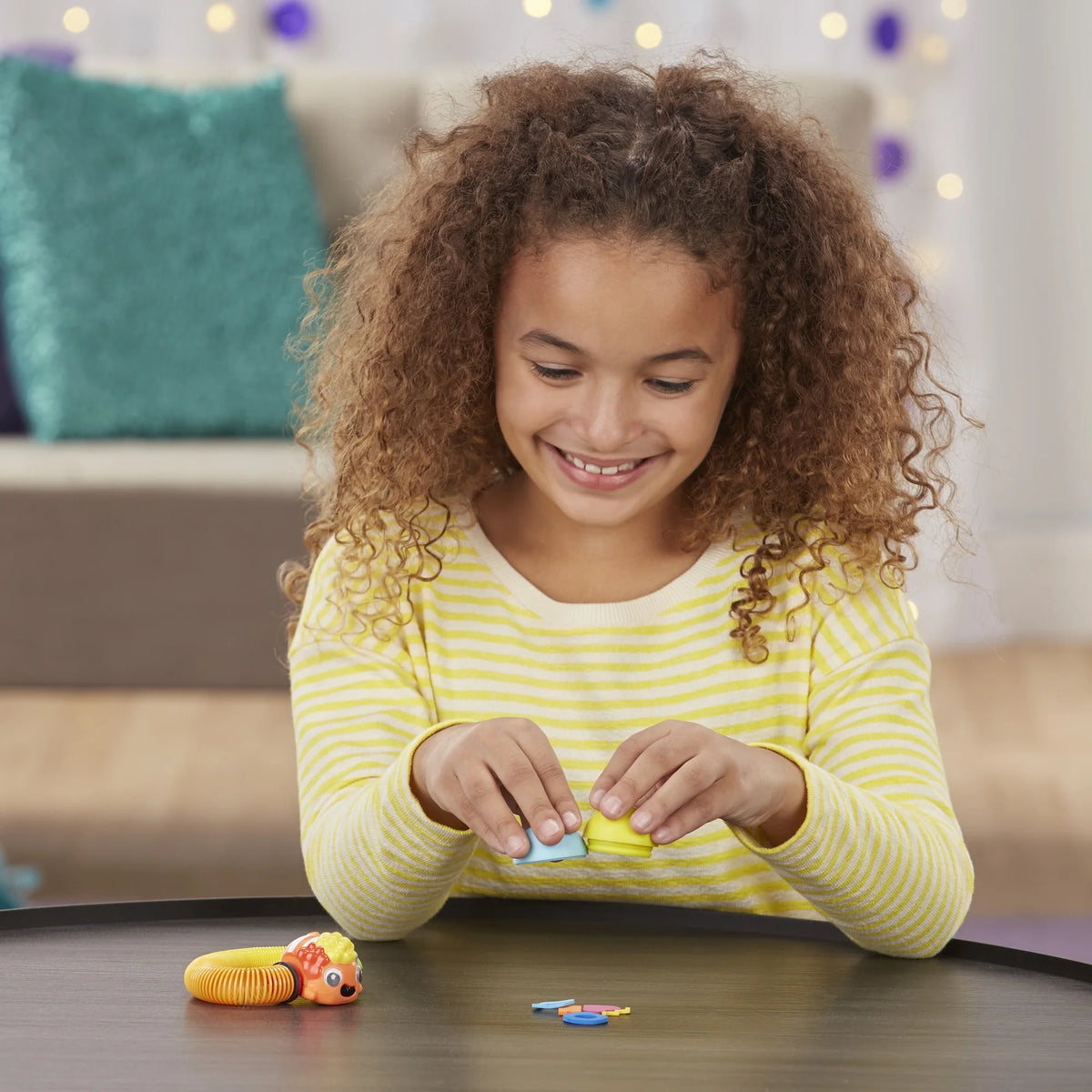 Smiling girl opening the blue and yellow ball beside the clownfish toy and foam shapes
