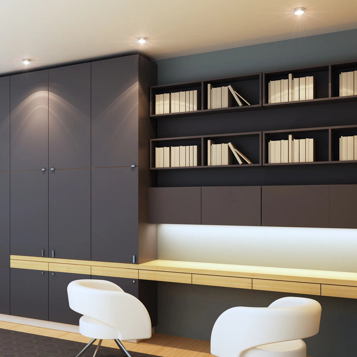 Recessed ceiling lights over dark cabinets and a wooden desk with white chairs