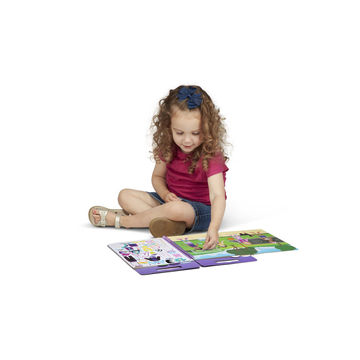 Toddler sitting on the floor dressing figures in the park scene with stickers