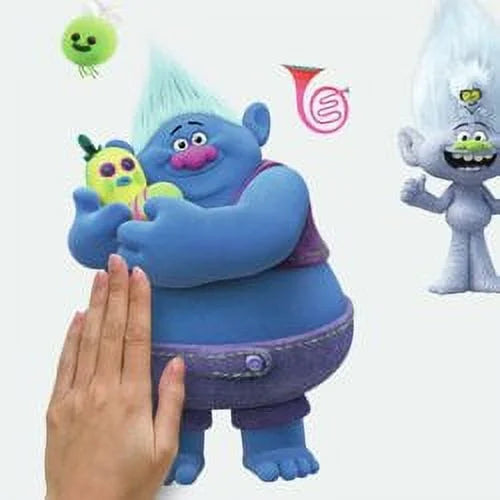 Hand pressing a blue troll decal holding a yellow critter onto a white wall