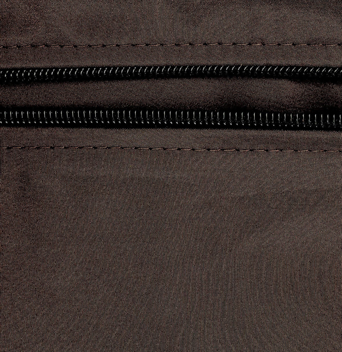 Macro view of the brown fabric weave and black zipper teeth