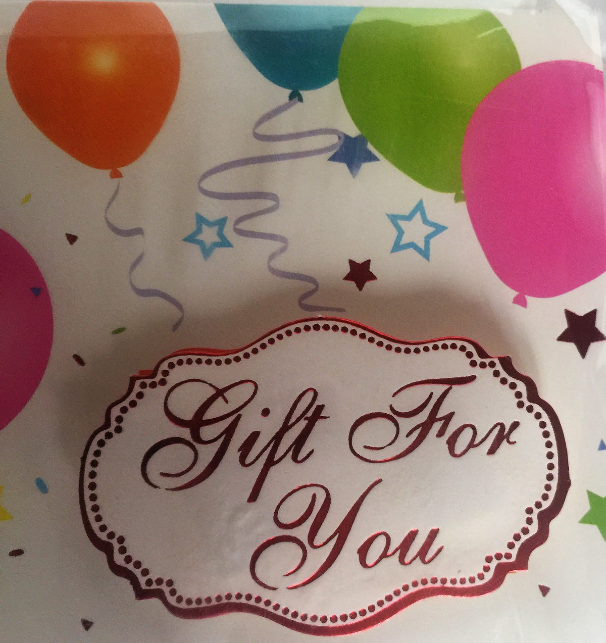 Close-up of the Gift For You script label over colourful balloons and stars
