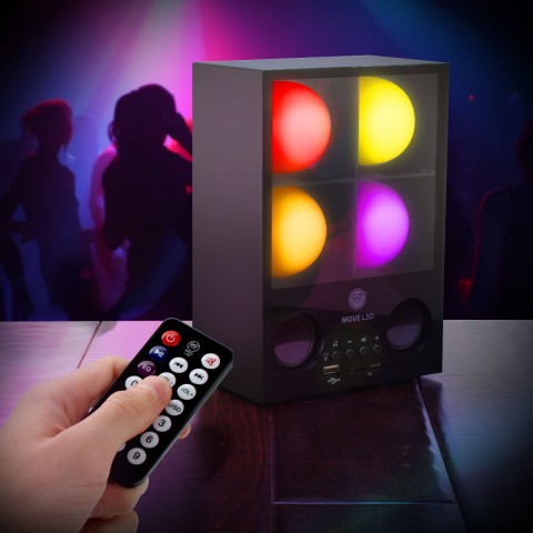 Hand pointing the remote at the glowing speaker on a bar with dancers behind
