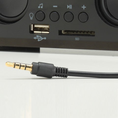 Close-up of the speaker's control buttons, USB port and SD slot with a 3.5 mm audio cable