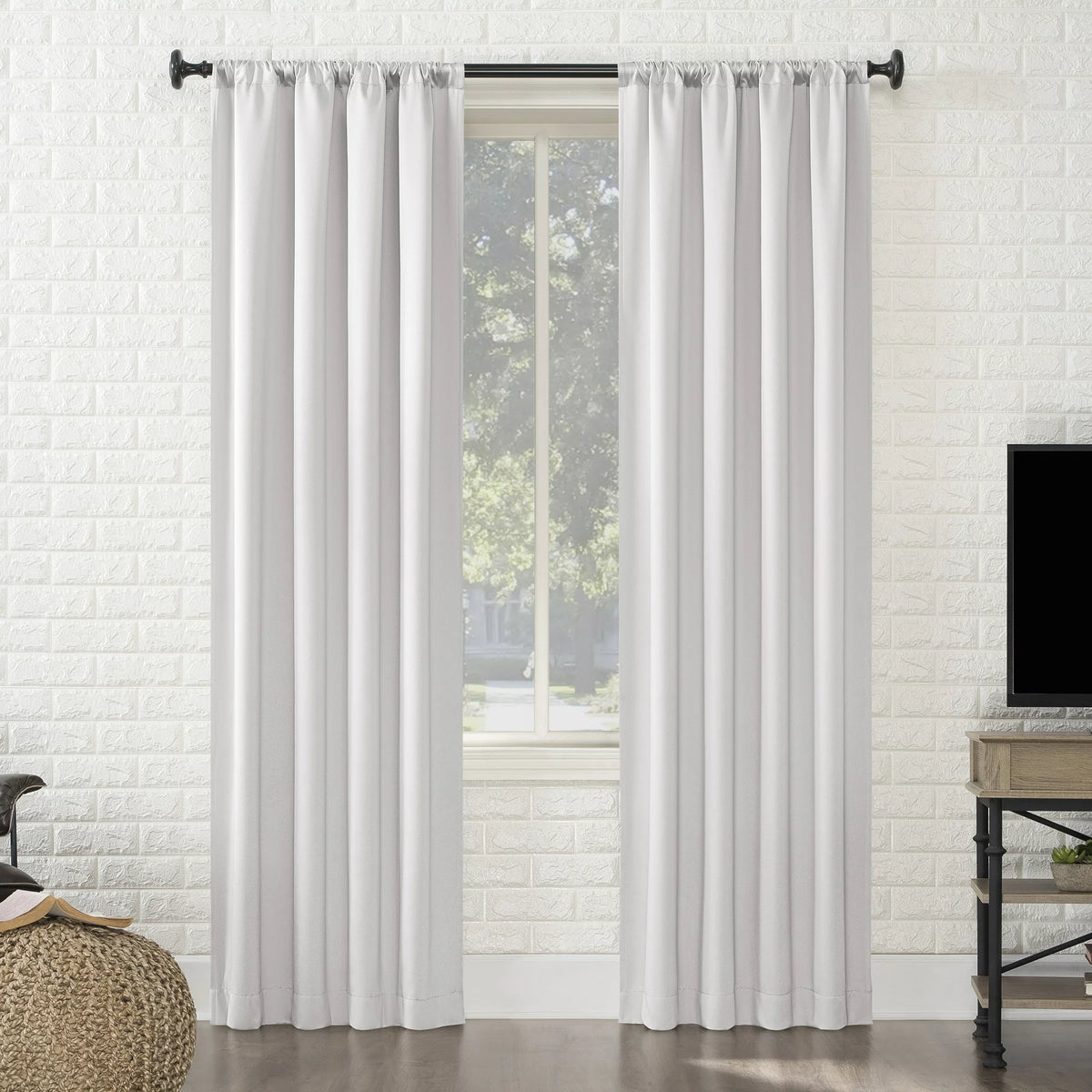 Two pearl white rod pocket blackout panels on a black rod by a window