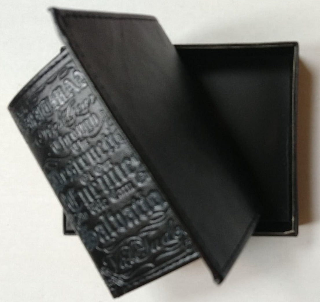 Black trifold wallet partly opened over its gift box