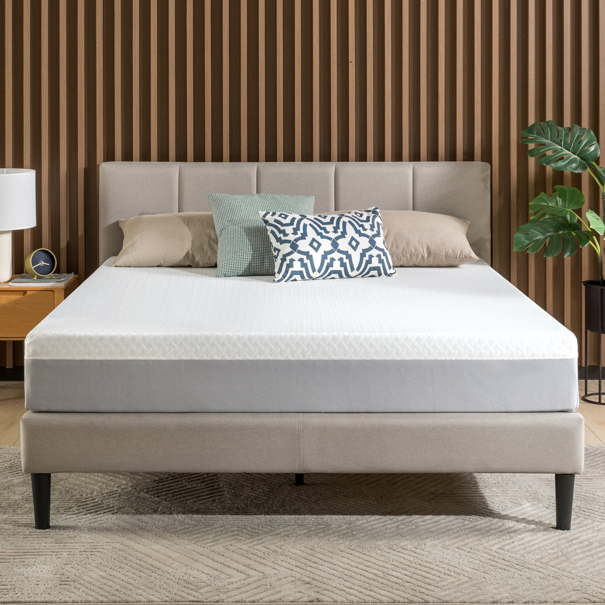 White and grey 8 inch mattress on an upholstered bed with pillows against a wood slat wall