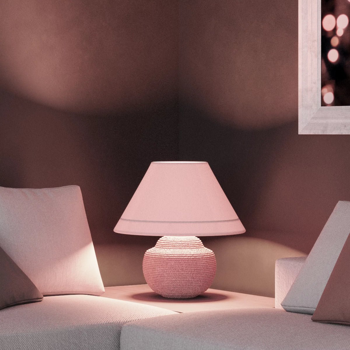 Table lamp glowing pink beside a white sofa in a dim room