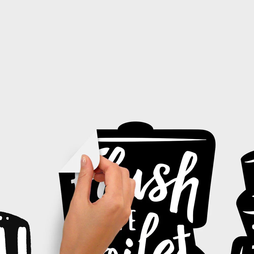Hand peeling the toilet-shaped Flush the toilet decal off a light grey wall