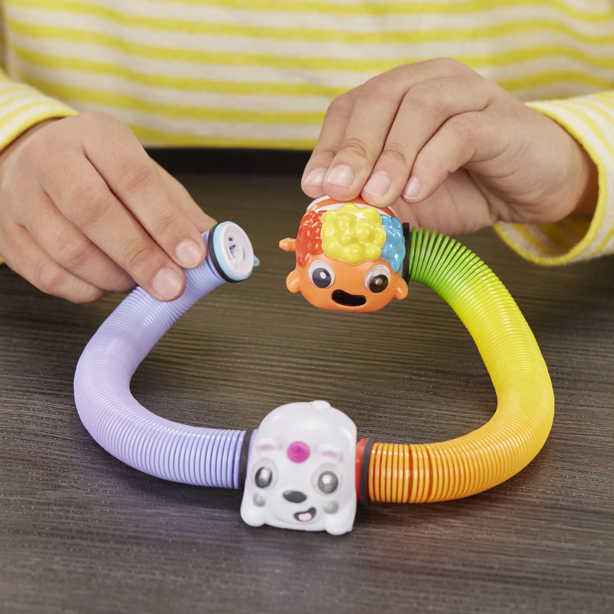 Hands connecting the clownfish spring to a purple spring with a white puppy head