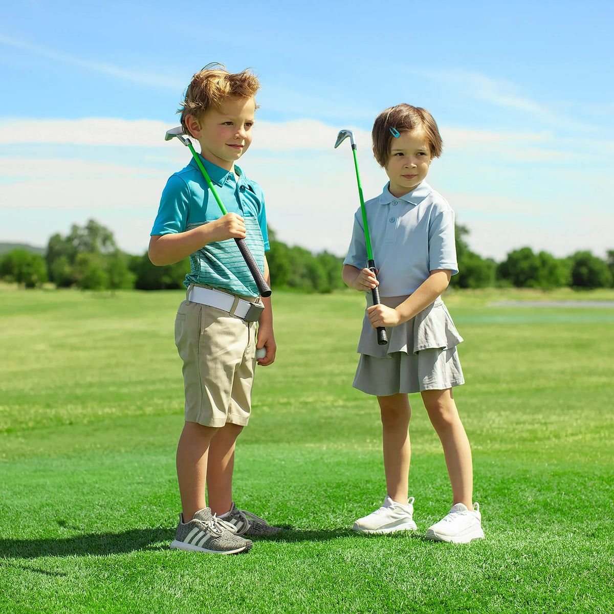 Boy and girl on a golf course holding a junior putter and iron with green shafts