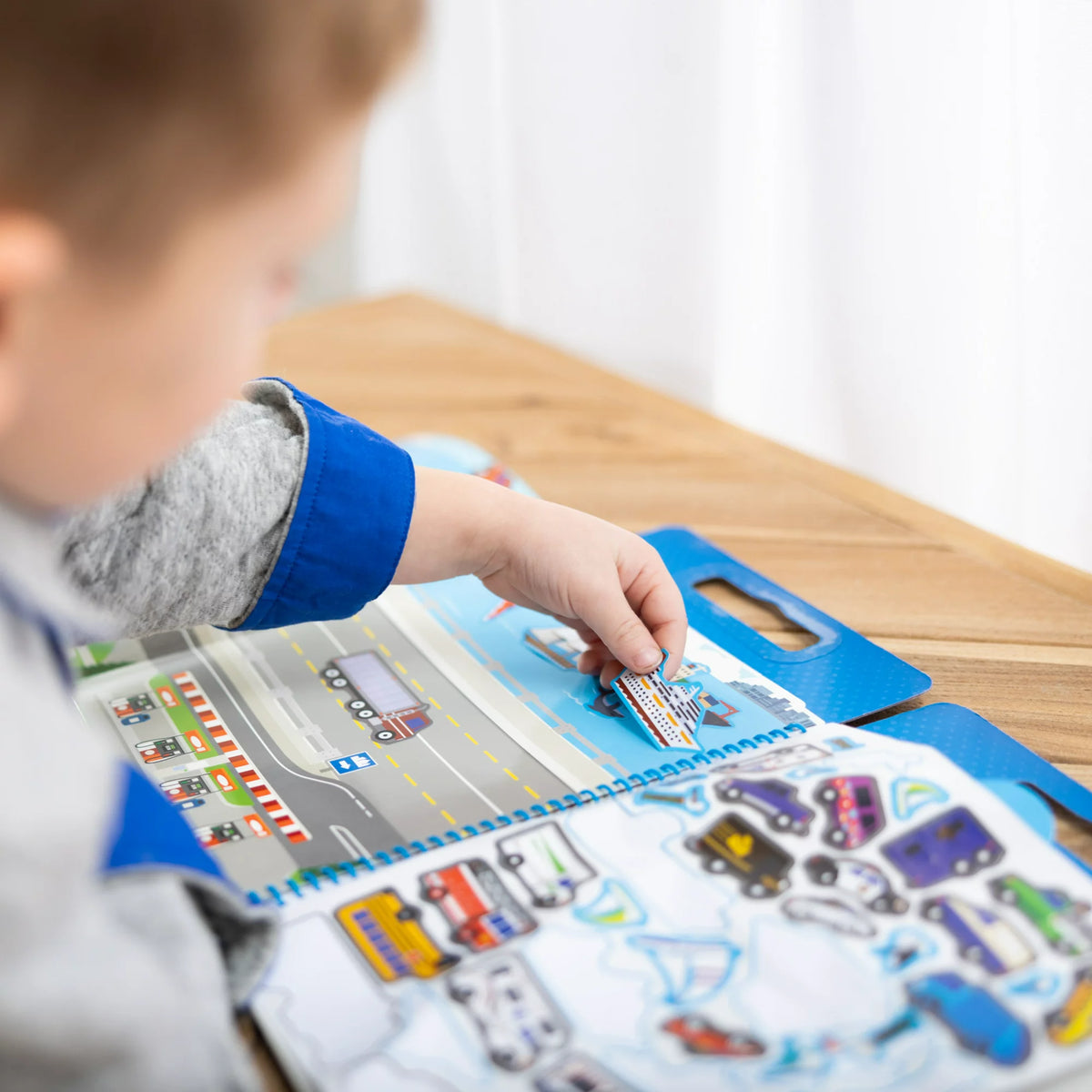 Close-up of a child's hand pressing a cruise ship sticker onto the water scene