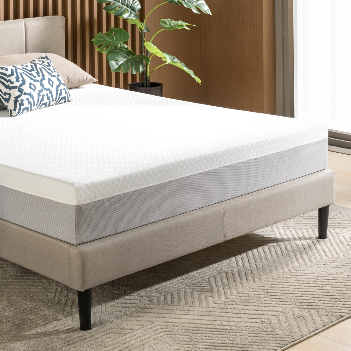 Corner view of the mattress on a beige upholstered bed frame