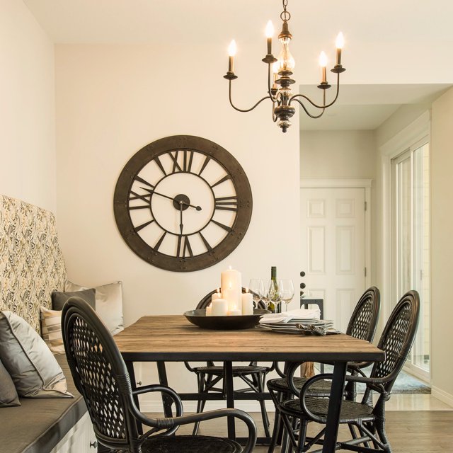 Bronze candle-style chandelier above a dining table by a large wall clock