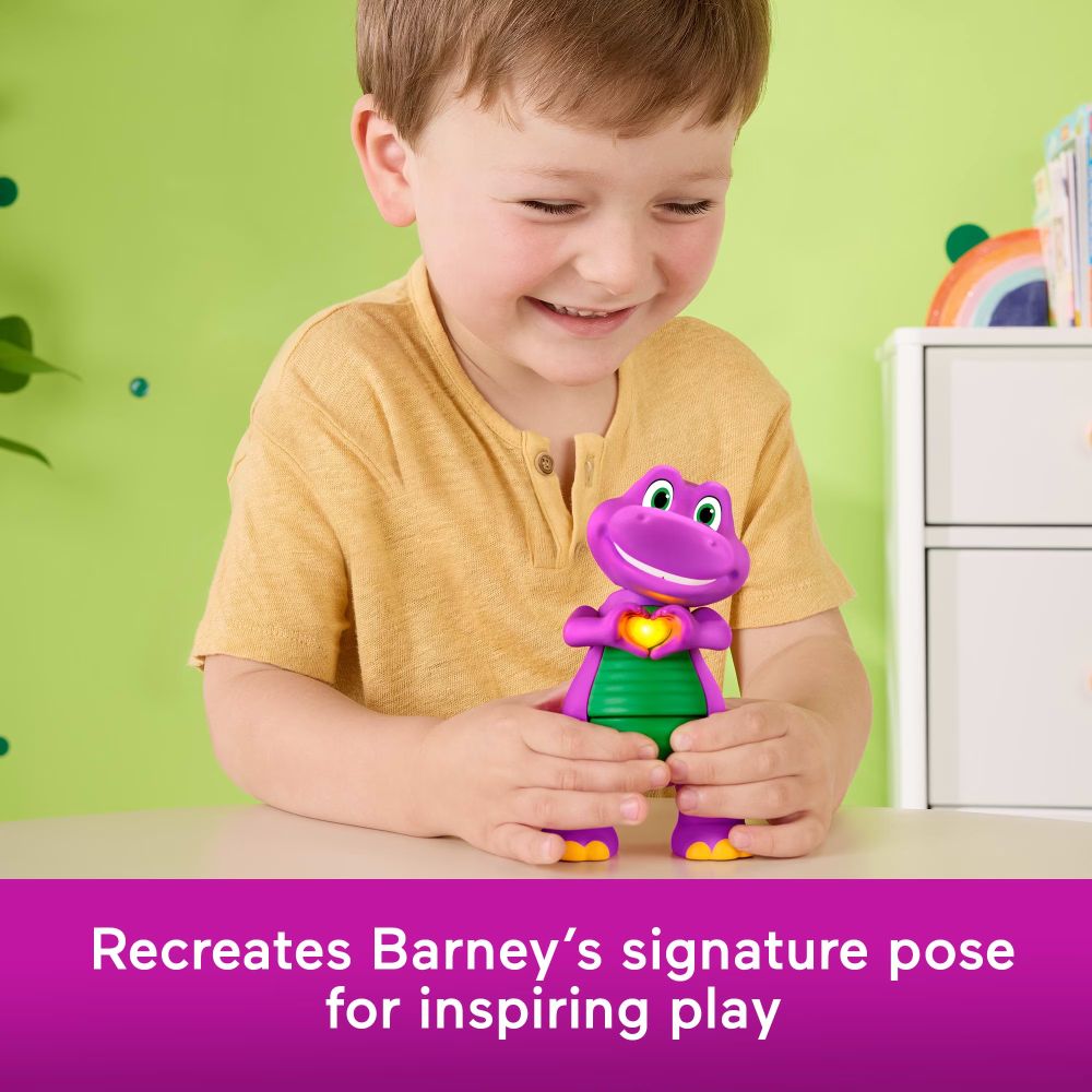 Smiling boy pressing Barney's belly at a table as his heart lights up