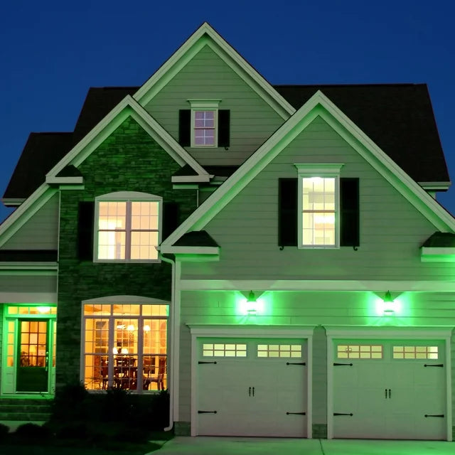 Two-storey house at night with green porch and garage lights