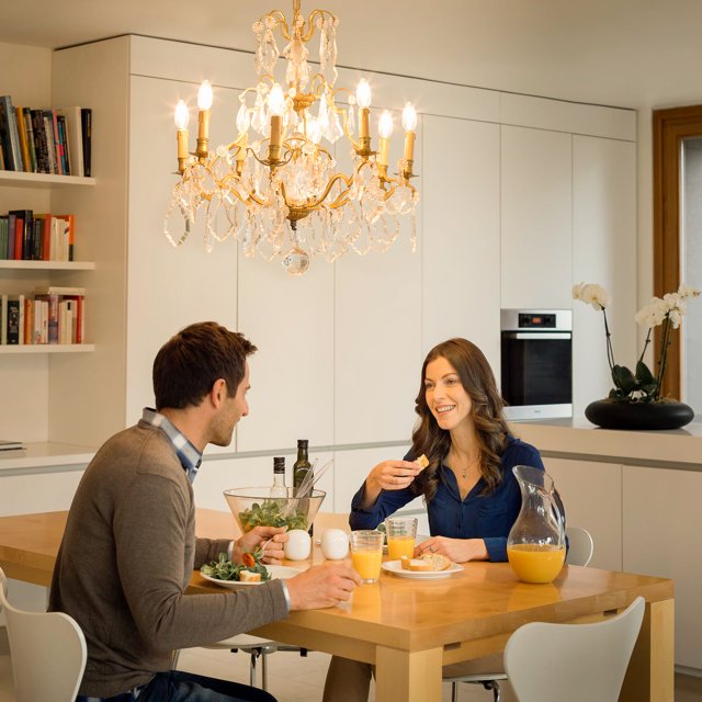 Couple at breakfast under a gold crystal chandelier with candle bulbs
