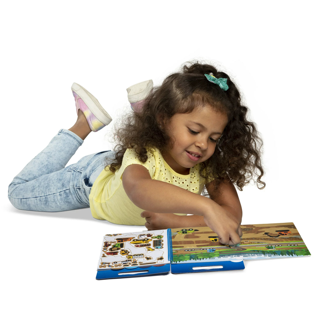 Girl lying on the floor adding stickers to the construction site scene