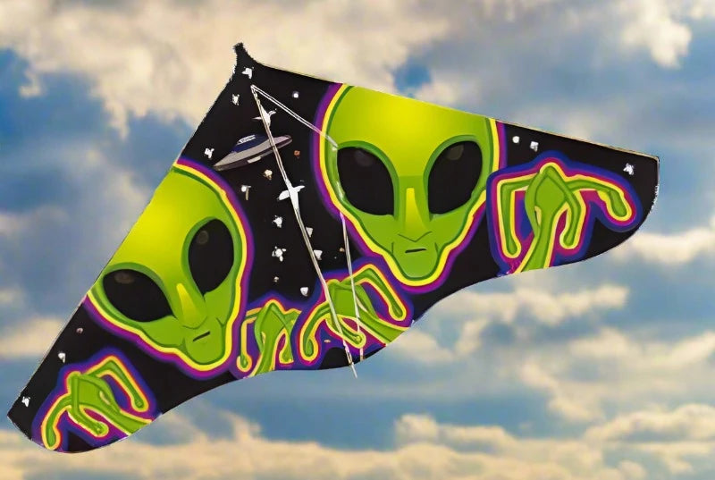 Green alien delta kite flying against a cloudy blue sky