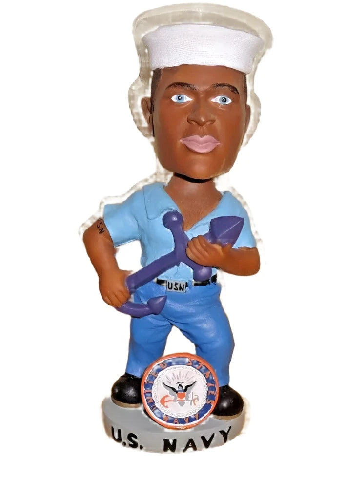Sailor bobblehead in a white cap and blue dungarees holding an anchor on a U.S. Navy base